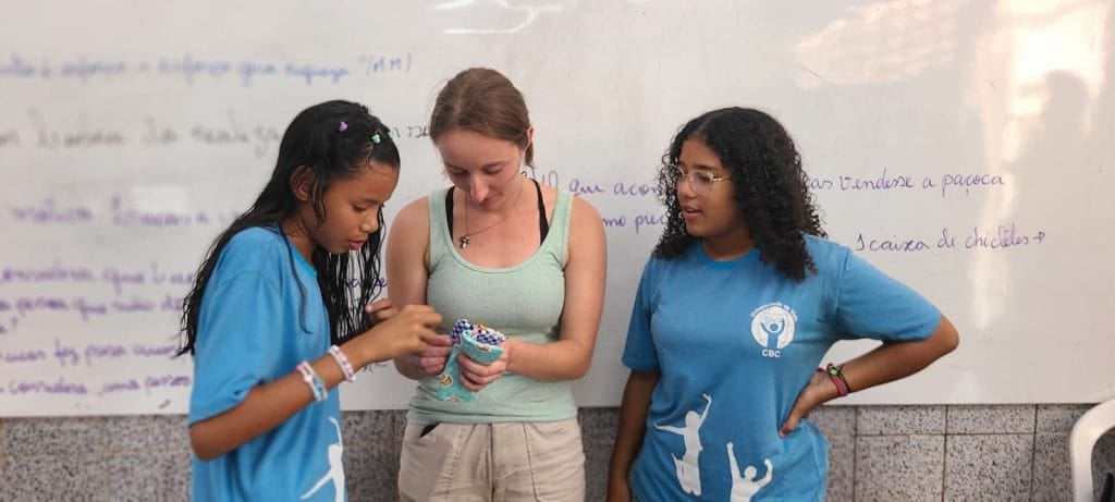 female volunteer and two students looking at little sewn bags