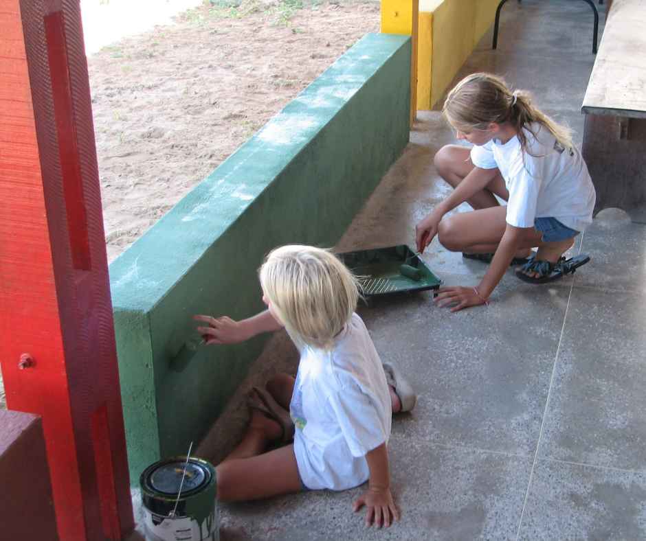 two girls painting walls in chapel area at cbc