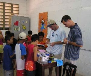 two male volunteers helping kids in classroom